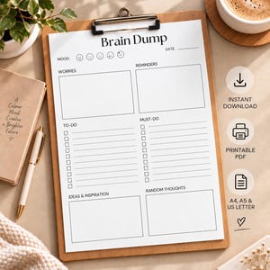 Op de afbeelding: Een wit papieren plannerblad met de titel Brain Dump op een houten klembord. De lay-out bevat secties voor stemming, datum, zorgen, herinneringen, taken, prioriteiten, ideeën en inspiratie, en willekeurige gedachten met vakjes en lijnen.