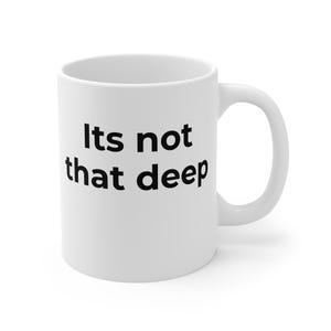 May include: A white ceramic mug featuring the black text Its not that deep printed on the front. The mug has a smooth cylindrical body, a wide opening at the top, and a curved handle on the right side, providing a simple and functional design.