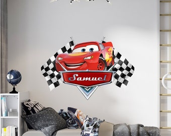 May include: Red cartoon race car with checkered flags and the name Samuel on a white wall. The car is smiling and has a black and white checkered flag on each side.