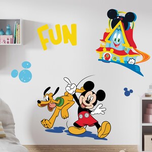 Puede incluir: Una calcomanía de pared amarilla con la palabra "FUN" en letras grandes. Mickey Mouse y Pluto caminan juntos. Mickey lleva pantalones cortos rojos y Pluto lleva un collar verde. Hay una casa azul y roja con una cara sonriente en el fondo.