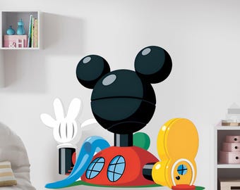 May include: A large wall decal featuring a cartoon character's head with three black spheres, a red house with blue windows, and a yellow structure. A white gloved hand and a blue slide are also included in the design.