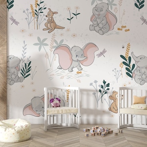 May include: A nursery room with a white crib, two white cribs with pink and yellow bedding, a white beanbag chair, a wooden bookshelf, and a wall mural featuring a jungle scene with elephants, kangaroos, and butterflies.