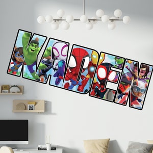May include: A wall decal featuring the name "KADEN" spelled out in large, black letters. Each letter is filled with a different superhero character from the Marvel universe, including Spider-Man, Iron Man, and Hulk.