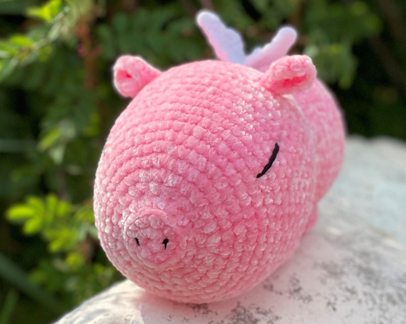 K&ouml;nnte beinhalten: Ein rosa geh&auml;keltes Stofftier mit einem Paar wei&szlig;en Geweih. Das Tier hat eine kleine schwarze Nase und Augen.
