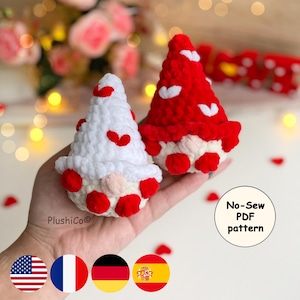 May include: Two handmade crochet gnomes, one white and one red, each adorned with red heart accents. The gnomes have beige faces and red feet. The image includes the text "No-Sew PDF pattern".