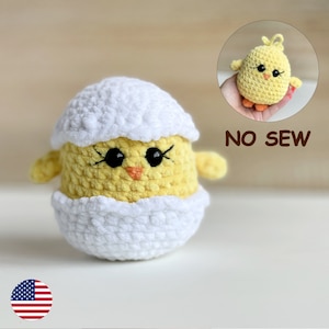 Puede incluir: Un pollito de crochet en una cáscara de huevo blanca. El pollito es amarillo con ojos negros y un pico naranja. El texto "NO SEW" es visible en la imagen.
