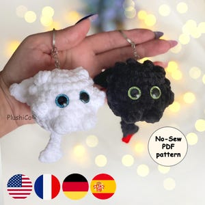 May include: Two handmade crochet keychains, one white and one black, each with large, googly eyes. The white keychain has blue eyes, and the black keychain has green eyes. The keychains are in the shape of a cartoon character. The image also includes the text "No-Sew PDF pattern".
