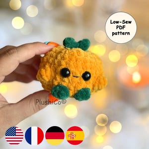 Peut inclure: Une citrouille orange en peluche avec des yeux noirs et un petit sourire. Des accents verts forment la tige et la base. Le texte "Low-Sew PDF pattern" est dans un cercle blanc. La marque "PlushiCo" est visible.