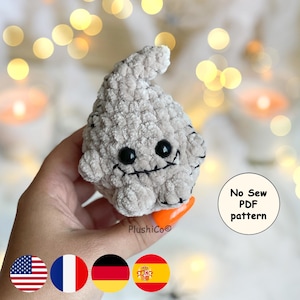 May include: A plush, light gray ghost with black eyes and a stitched mouth. The ghost has a rounded body and a small, pointed head. The text "No Sew PDF pattern" is visible. The image also includes the American flag.