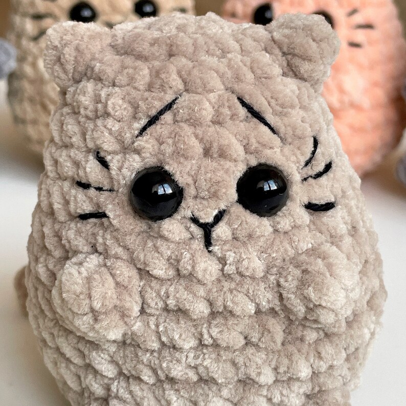 May include: A plush, gray crocheted cat toy with black embroidered eyes and whiskers.