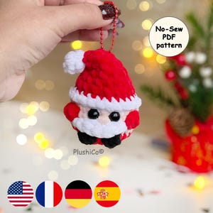 May include: A handmade crochet Santa Claus ornament with a red hat and suit, white beard and trim, and black eyes and boots. The ornament is attached to a red chain. Text on the image says "No-Sew PDF pattern".