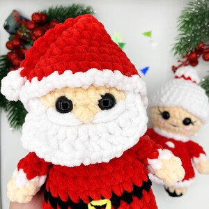 Puede incluir: Un mu&ntilde;eco de crochet de Pap&aacute; Noel con un gorro rojo, barba blanca y cintur&oacute;n negro. El mu&ntilde;eco tiene ojos negros de bot&oacute;n y un borde blanco alrededor del gorro.