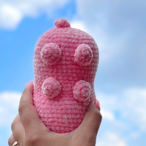 K&ouml;nnte beinhalten: Ein rosa geh&auml;keltes Stofftier mit einer strukturierten Oberfl&auml;che und vier gro&szlig;en, runden, flauschigen Noppen.