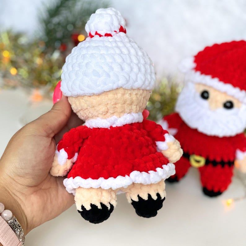 Puede incluir: Un conjunto de mu&ntilde;ecas de crochet de Pap&aacute; Noel y la se&ntilde;ora Claus. Las mu&ntilde;ecas est&aacute;n vestidas de rojo y blanco con zapatos negros. La mu&ntilde;eca de la se&ntilde;ora Claus lleva una bolsa roja.