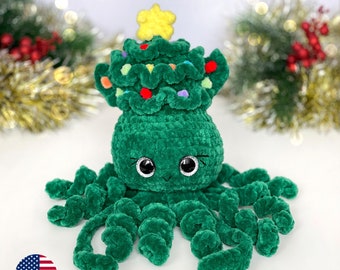 Könnte beinhalten: Ein grüner gehäkelter Oktopus, der einen grünen und roten Weihnachtsbaumhut mit einem gelben Stern oben trägt. Der Oktopus hat große, schwarze Augen und einen freundlichen Ausdruck.