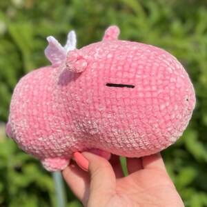 K&ouml;nnte beinhalten: Ein rosa geh&auml;keltes Stofftier mit wei&szlig;en Fl&uuml;geln. Das Tier hat einen kleinen schwarzen Mund und Augen.