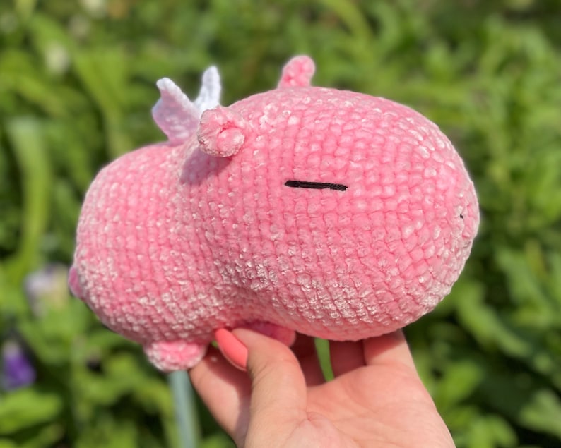K&ouml;nnte beinhalten: Ein rosa geh&auml;keltes Stofftier mit wei&szlig;en Fl&uuml;geln. Das Tier hat einen kleinen schwarzen Mund und Augen.