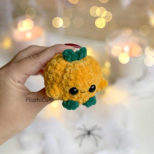 May include: A plush, orange pumpkin with a smiling face, green stem, and green feet. The handmade, crocheted pumpkin is a cute Halloween decoration. The product is made by PlushiCo.