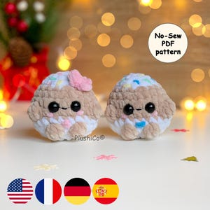 Op de afbeelding: Twee handgemaakte pluche speelgoed, bruin en wit, met zwarte ogen en kleurrijke sprinkles. Eén heeft een roze strik, de andere een blauwe strik. De tekst "No-Sew PDF pattern" staat in een witte cirkel. De merknaam "PlushiCo" is zichtbaar.