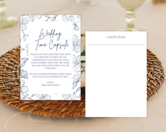 Puede incluir: Una tarjeta blanca con un borde floral azul y el texto "Wedding Time Capsule". La tarjeta instruye a los invitados a escribir un mensaje para abrir en su aniversario. Una tarjeta blanca en blanco con el texto "A Note From:" está a su lado.
