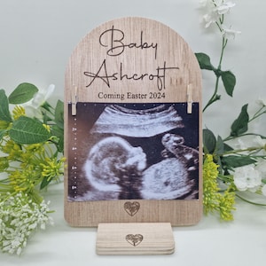 May include: Wooden photo frame with a white background and the text "Baby Ashcroft Coming Easter 2024". A black and white ultrasound image is displayed in the frame.