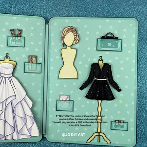 Puede incluir: Un conjunto de mu&ntilde;ecas de papel imprimibles con una variedad de opciones de ropa, que incluyen un vestido blanco, un vestido negro, un bolso y zapatos. La mu&ntilde;eca es una figura femenina con cabello rubio. La imagen incluye el texto "ATTENTION! The picture Shows the finished product After Printen and assembling. You will only receive a PDF with video instruction. It is a DIY Download. @JG DIY ART"