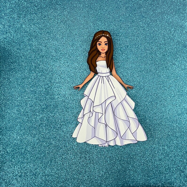Puede incluir: Un vestido de novia blanco con una falda con volantes y un corpi&ntilde;o sin tirantes. El vestido lo lleva una mujer con el pelo largo y casta&ntilde;o y una tiara.