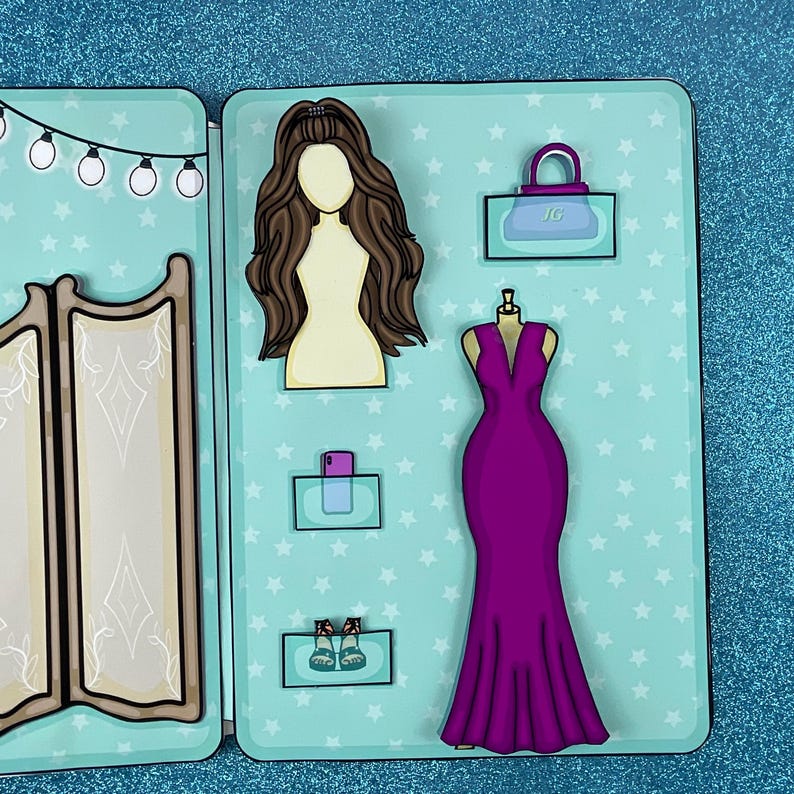 Puede incluir: Un juego de vestir de color azul turquesa con un espejo, un vestido, zapatos, un bolso y un tel&eacute;fono. El vestido es morado, los zapatos son marrones, el bolso es azul turquesa con un asa dorada y el tel&eacute;fono es morado.