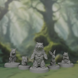 Peut inclure: Cinq figurines miniatures d'animaux, peintes en gris, sont présentées sur des socles individuels. Les figurines comprennent un ours, un lapin, un écureuil, un chat et un loup. Les figurines sont placées sur un fond flou de forêt.