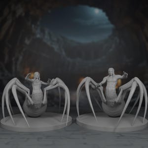May include: Two grey 3D-printed figurines of humanoid creatures with spider-like bodies. Each figure has a human torso and head, with multiple legs extending from a bulbous abdomen. They stand on circular bases, set against a blurred, cave-like background.
