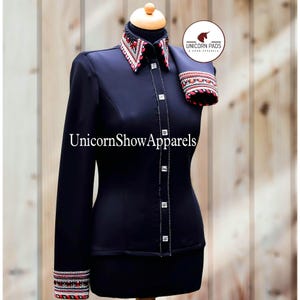 May include: Black long-sleeve show shirt with a red and white patterned collar and cuffs. The shirt has a row of silver buttons down the front and is embellished with rhinestones. The text "UnicornShowApparels" is printed on the front of the shirt. The text "Unicorn Pads & Show Apparel" is printed on a white circle with a unicorn logo.