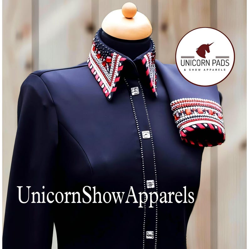 May include: A black long-sleeve shirt with a red, white, and black embellished collar and matching cuff. The shirt has a button-up front and is adorned with silver rhinestones. The text "UnicornShowApparels" is printed on the front of the shirt.