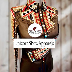 May include: A brown show shirt with red, gold, and black geometric embroidery. The shirt has a collar and long sleeves. The text "Unicorn Pads & Show Apparels" is on a white label on the front of the shirt.