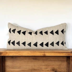 May include: A black and white geometric patterned throw pillow on a wooden bench.