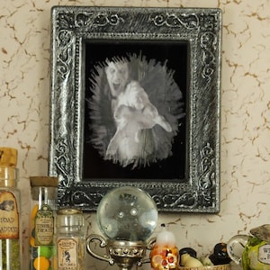 May include: A miniature black shelf with two shelves, decorated with a variety of Halloween-themed items, including a crystal ball, potion bottles, a skull, and a caged bird. The shelf is set against a textured beige wall with a framed picture above it.