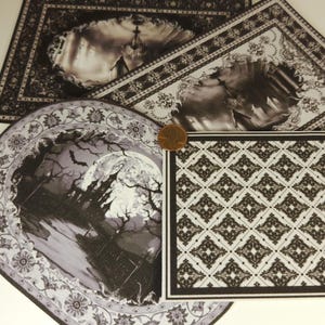 May include: A collection of rectangular and oval paper cards featuring black and white gothic illustrations of a haunted mansion, a full moon, bats, and ornate damask patterns. A copper-colored penny is placed on the edge for scale reference.