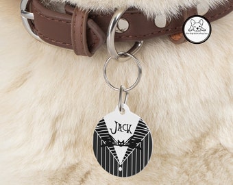 May include: White round dog tag with a black and white striped pattern and a black cat face. The tag says "Jack" in black text. The tag is attached to a brown leather dog collar.