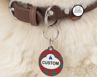 May include: A round, red, white, and blue plaid dog tag with a white oval and the word "CUSTOM" in black text. The oval also features a blue silhouette of a castle.