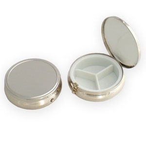 May include: A silver pill box with a mirrored lid and a three-compartment interior.