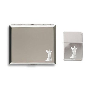 May include: A silver compact mirror and lighter set. Both items feature a decorative silhouette of a dancing couple. The compact mirror is rectangular with a hinged lid. The lighter is a classic rectangular shape.
