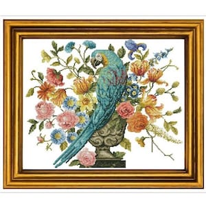 May include: A blue and green parrot perched on a vase filled with colorful flowers. The vase is decorated with a floral pattern and sits on a white background.