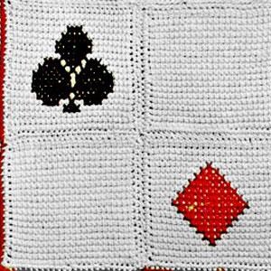 Pode incluir: Um quadrado branco de crochê com um trevo preto e um diamante vermelho no centro.