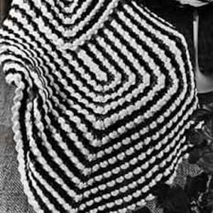 May include: Black and white crocheted shawl with a geometric pattern. The shawl features a square shape with a hood and a textured, striped design. The color scheme is a classic combination of black and white.