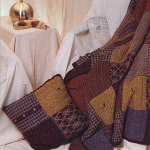 May include: A patchwork quilt made of different fabrics in shades of brown, beige, and purple. The quilt is folded and draped over a chair with a newspaper on it. There is a pillow made of the same fabric on the chair.
