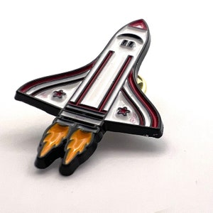 Space Ship pin. White space ship shaped pin badge with coloured detail enamel pin badge.