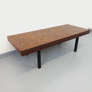 May include: A rectangular coffee table with a dark wood top and black legs. The tabletop has a mosaic-like pattern. The table is approximately 48 inches long, 20 inches wide, and 16 inches high.