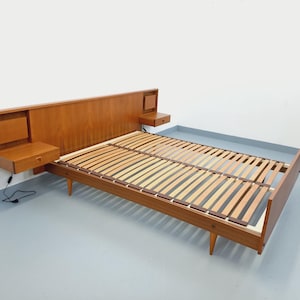 May include: A mid-century modern wooden bed frame with a headboard and two attached nightstands. The bed frame has a slatted base and tapered legs. The headboard and nightstands are a warm wood tone.
