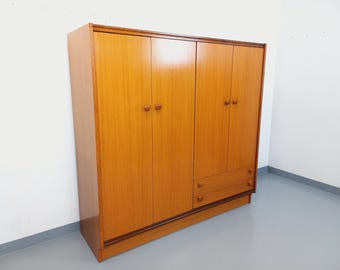 Puede incluir: Un armario de madera de cuatro puertas con dos cajones en la parte inferior. El armario está hecho de madera clara con un acabado natural.