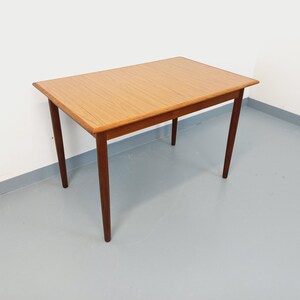 Puede incluir: Una mesa rectangular de madera con una tapa de color marrón claro y patas de color marrón oscuro. La mesa tiene un diseño simple y minimalista, adecuado para varios estilos de interior. La mesa mide aproximadamente 100 cm de largo, 60 cm de ancho y 70 cm de alto.