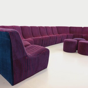 May include: A modular sectional sofa with a curved design. The sofa is upholstered in a purple fabric with pink stripes. The sofa includes three matching purple ottomans.